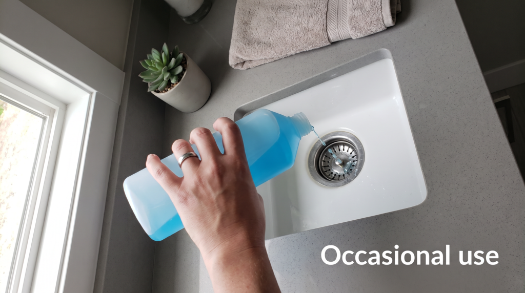 Hand pouring chemical drain cleaner into a bathroom sink in a home with a septic system